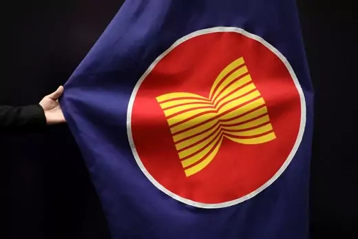 A hand stretches out the blue, red, white, and yellow ASEAN flag during the organization's latest meeting.