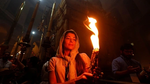 Orthodox Christian woman lighting a torch at the Holy Fire Ceremony in Jerusalem 