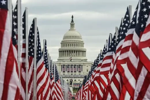 The U.S. Capitol Building is flanked by two rows of U.S. flags. 