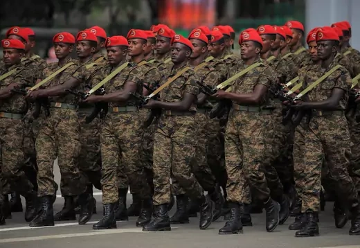 Ethiopian soldiers wearing red berets and military fatigues march while toting assault rifles.