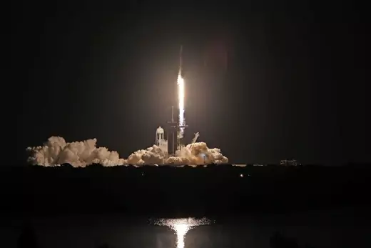 A rocket ship takes off at night. 