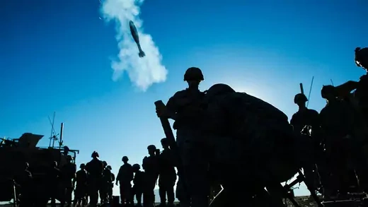 Silhouette of a group U.S. soldiers and a mortar flying out of a tube in Afghanistan.