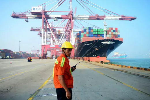 A Chinese worker looks on as a cargo ship is loaded at a port in Qingdao, eastern China's Shandong province on July 13, 2017.