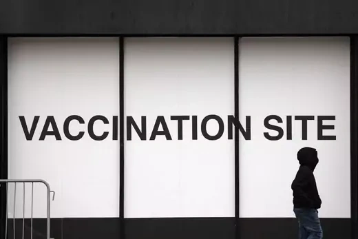A person walks past a vaccination site as the Omicron coronavirus variant continues to spread in Brooklyn, New York City