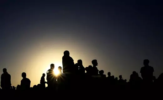 Silhouettes of a group of Ethiopian civilians are seen in front of a setting sun in the background.