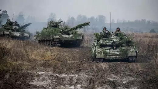 Ukrainian soldiers ride on three green tanks during tactical drills at an open field in Ukraine.