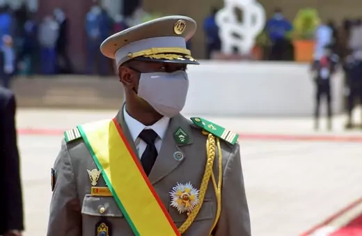 Mali's new interim president walks during his inauguration wearing formal military attire and a sash with the Malian flag's colors.  