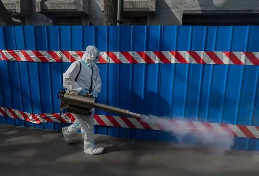 A health worker wears a protective suit as he disinfects an area outside a barricaded community that was locked down for health monitoring after recent cases of COVID-19 were found in the area on March 28, 2022 in Beijing, China.