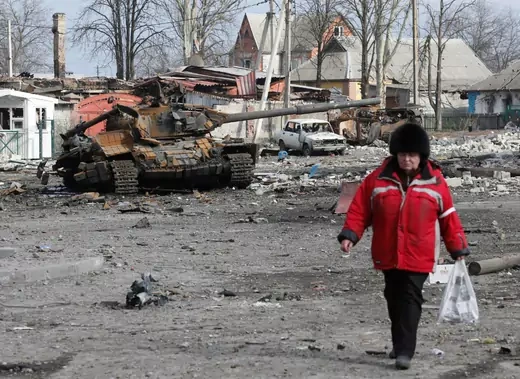A woman walks past a destroyed tank in a street damaged during Ukraine-Russia conflict in the separatist-controlled town of Volnovakha in the Donetsk region, Ukraine March 15, 2022. 