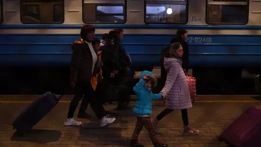A group of Ukrainian refugees walk along the platform at a train station in Poland.