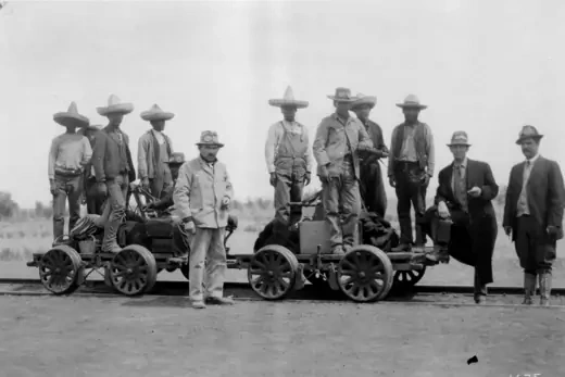 Photo of Mexican railroad workers in the 1880's, standing on tracks.