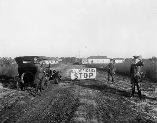U.S. Border Patrol agents, holding up a sign that reads "U.S. officers, Stop", block a road in Gainesville, Florida, in 1926.