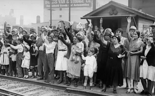 People on the side of railroad track, wave goodbye to Mexicans being expelled to Mexico.