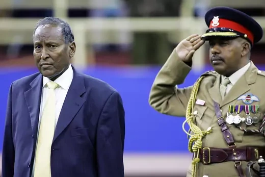 New elected Somali President Abdullahi Yusuf looks on as the Somali flag is hoisted during a swearing in ceremony in Nairobi, as a military officer salutes.