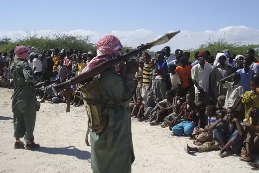 Militants of al Shabaab display weapons in front of people on a street in the outskirts of Mogadishu