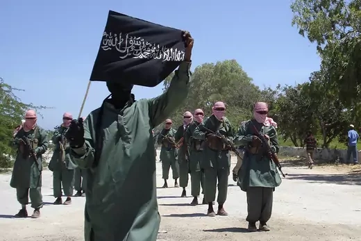 Al-Shabab fighters carrying flags and wepons, march on the outskirts of Mogadishu.