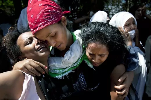 Three women mourn during a memorial service for Eritreans killed by bomb attack.