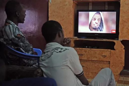 A photo showing two men sitting and watching a CNN news broadcast showing the face of slain al-Shabab leader Ahmed Abdi Godane.