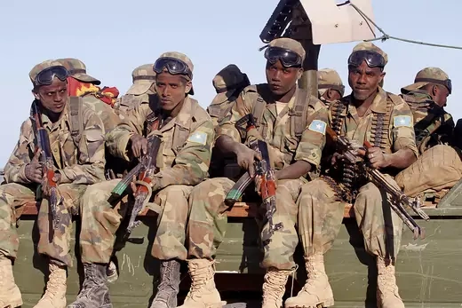 Somali soldiers with machine guns sitting on truck.