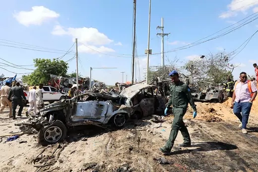 A Somali police officer walks past wreckage at the scene of a car bombing in Mogadishu on December 28, 2019.