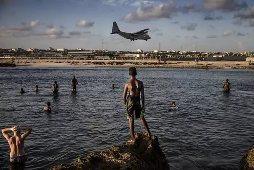 Beachgoers watch a military plane landing at Mogadishu's airport.