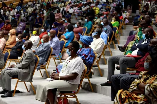 Worshippers attending mass wear face masks and sit in individual chairs six feet away from each other.