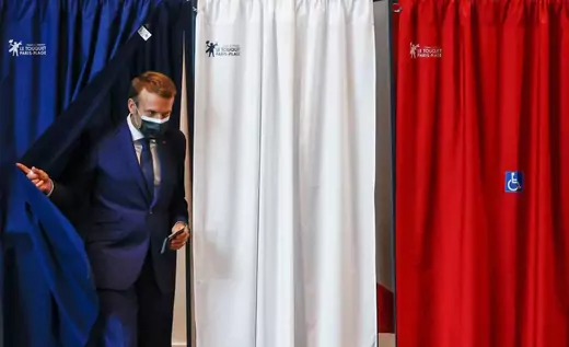 French President Emmanuel Macron leaves the polling booth by pulling an anti-covid curtain before he votes at the polling station in Le Touquet, for the first round of the French regional elections on June 20, 2021.