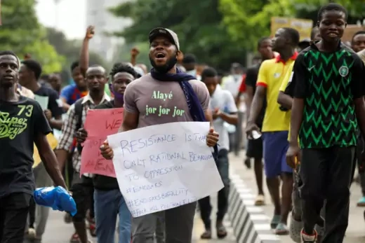 Nigerian protestors walk the streets with posters in hand. 