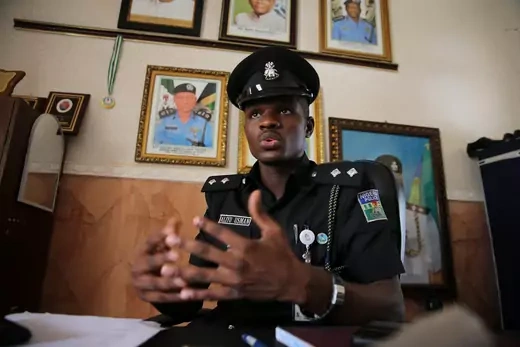 Nigerian police officer sitting down being interviewed wearing police outfit. 