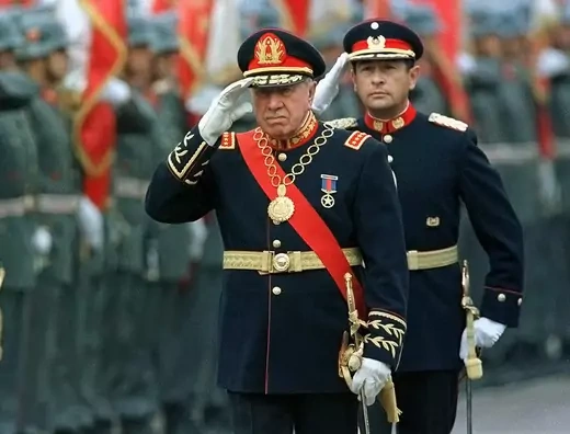 Chilean dictator Augusto Pinochet is seen in uniform doing a military salute.