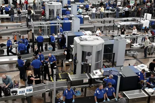 TSA workers conduct security checks, including full-body scans.