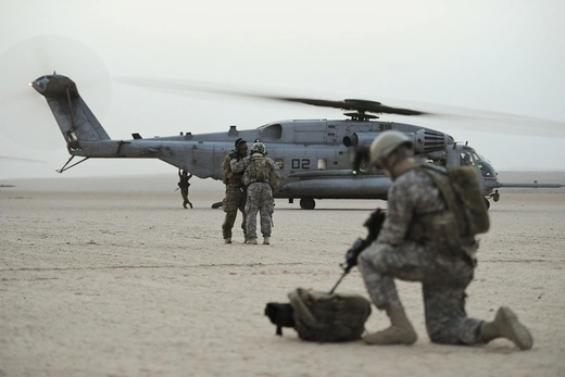 U.S. Army and Air Force service members with helicopter in desert.