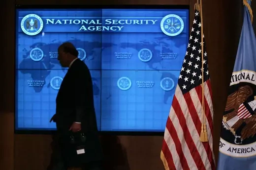 U.S. National Intelligence Director John Negroponte walks past a video screen.