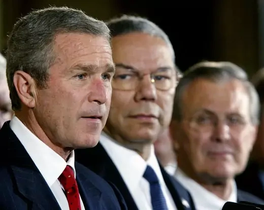 U.S. President George W. Bush speaks while Secretary of State Colin Powell (C) and Secretary of Defense Donald Rumsfeld look on.