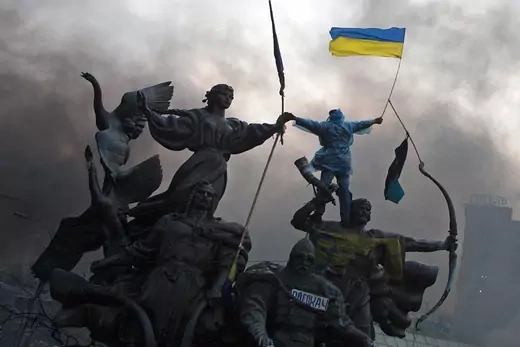  A protester waves the Ukrainian flag from the top of a statue during clashes with riot police in Independence Square in Kyiv.