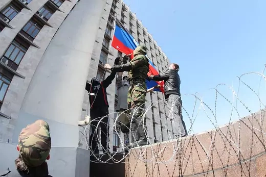 Pro-Russia activists raise the flag of the so-called Donetsk People’s Republic.