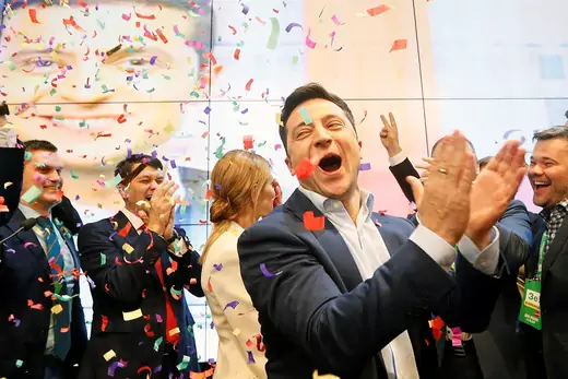 Volodymyr Zelensky surrounded by supporters claps his hands as he celebrates the announcement of the first exit poll at his campaign headquarters.