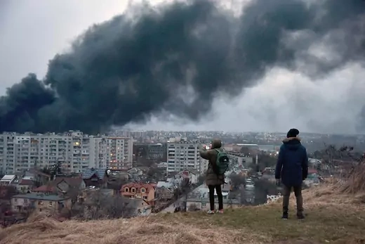 Two people watch as smoke rises on buildings from Russian airstrike in Lviv, Ukraine