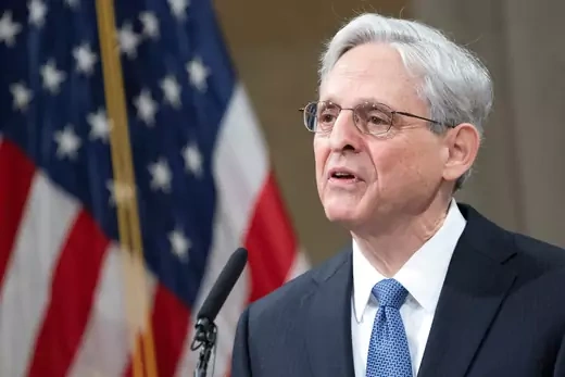 Merrick Garland speaks in front a podium with an American flag in the background.