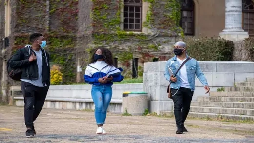 Students walking with face masks on a university campus.