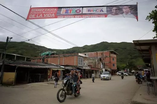 A family rides a motorcycle under a banner depicting Colombian presidential candidate for the Pacto Historico coalition Gustavo Petro and his running mate Francia Marquez, in her native town Suarez, Cauca department, Colombia, on May 25, 2022.