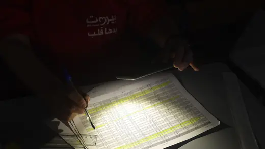 A poll worker uses light from a cell phone to count votes from Lebanon's 2022 general election in the dark