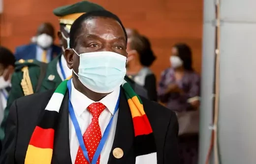 Zimbabwe's President wears a suit, a red tie, and a scarf with the colors of the Zimbabwean flag. He is also wearing a facemask 