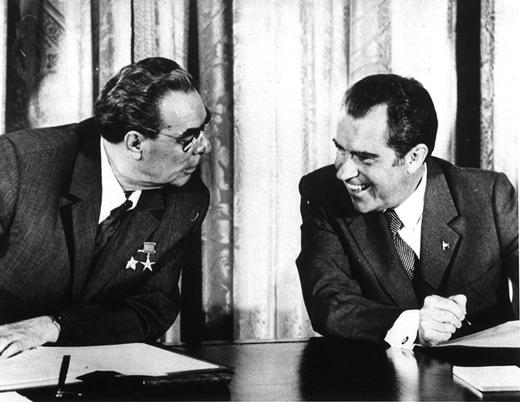 Photo showing U.S. President Richard Nixon and Soviet leader Leonid Brezhnev sitting at table talking and smiling.