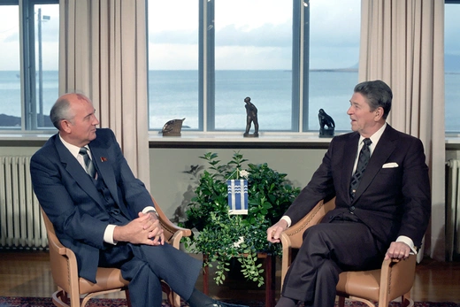 Photo showing U.S. President Reagan with Soviet General Secretary Gorbachev sitting in front of a window with a view of the sea, talking. 