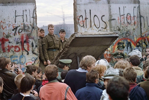 Photo showing West Berliners crowd in front of the Berlin Wall early 11 November 1989 as they watch East German border guards demolishing a section of the wall in order to open a new crossing point between East and West Berlin, near the Potsdamer Square. 