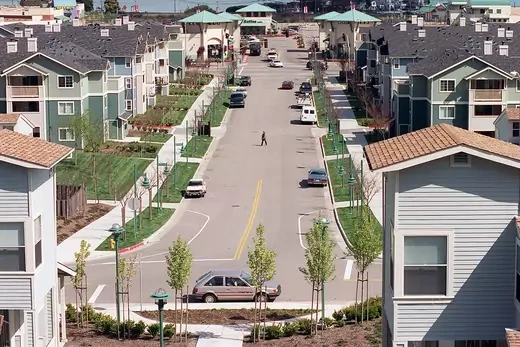 A view of a person walking across a street in a housing development in California.