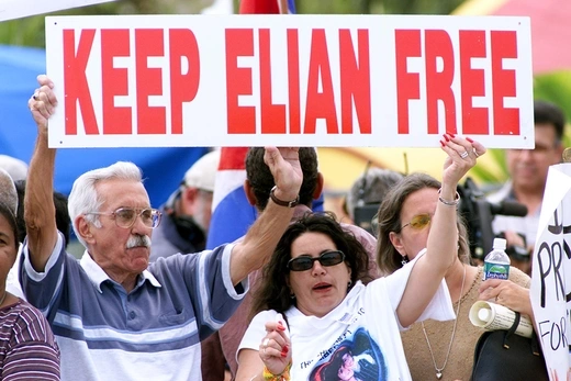 Demonstrators display a sign saying "Keep Elian Free" over a barricade next to the home of six-year-old Elian Gonzalez at his great-uncle's home in Little Havana