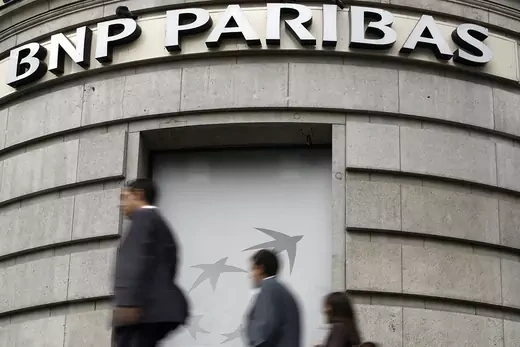 Photo showing 3 people walking under a BNP Parisbas sign.