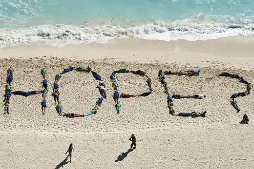 Environmental activists lay on a beach and spell out 'Hope?' with their bodies.